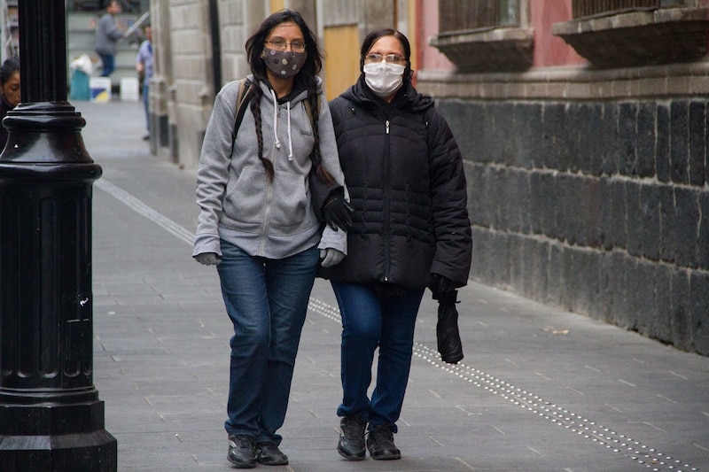 Dos mujeres caminan por la calle con mascarillas