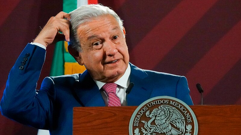 El presidente López Obrador se rasca la cabeza durante una conferencia de prensa.