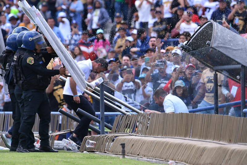 La policía detiene a un aficionado en un partido de fútbol.