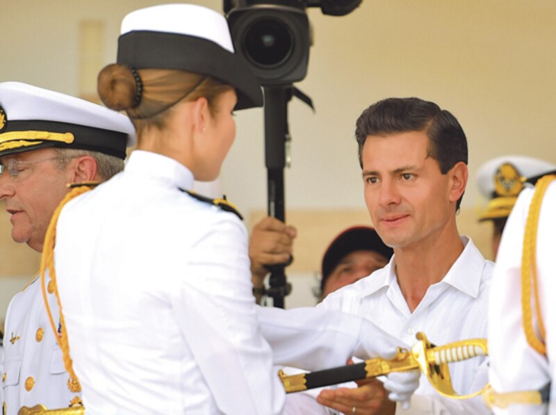 El presidente Enrique Peña Nieto entrega una espada a una mujer militar durante una ceremonia.