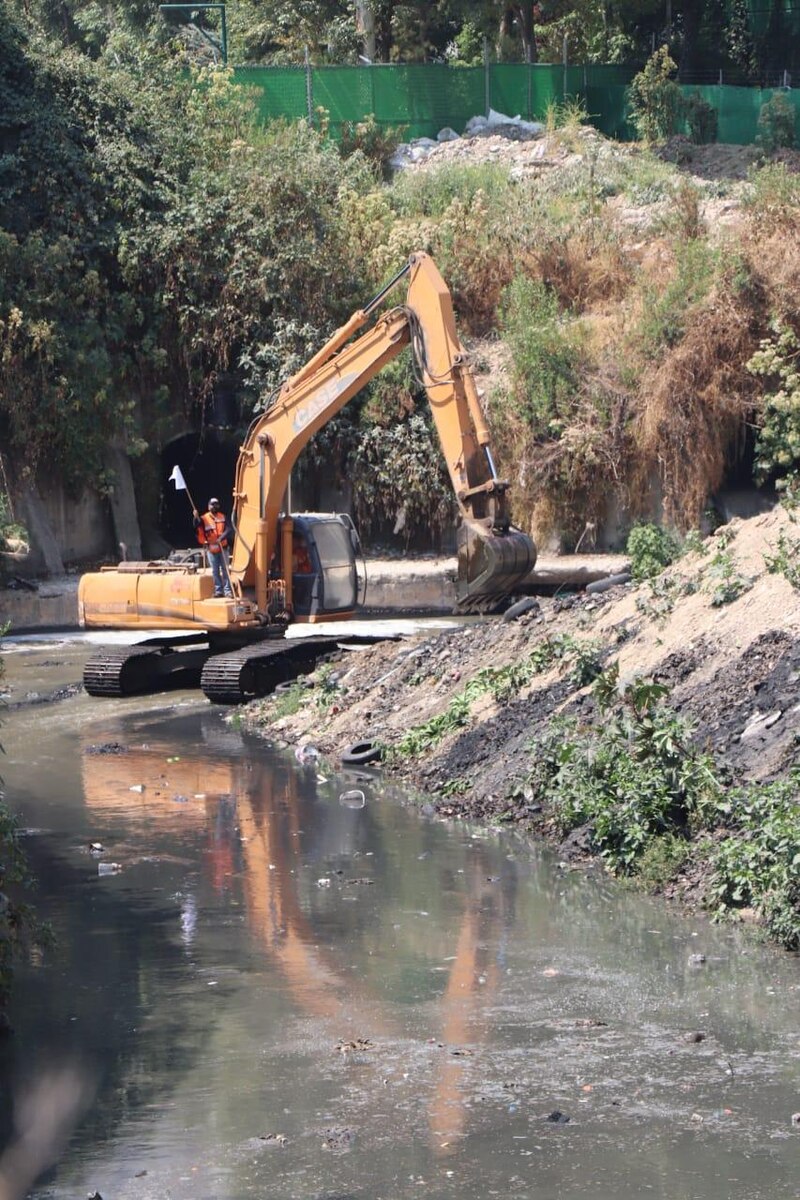 Excavadora trabajando en un río contaminado