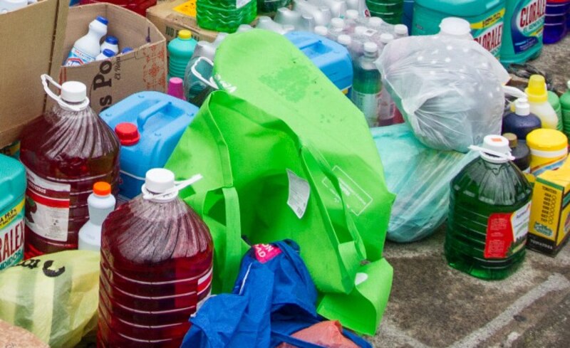 Una imagen de una bolsa de plástico verde llena de botellas de plástico.