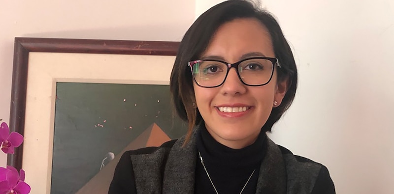 Mujer joven con gafas sonríe frente a una pintura