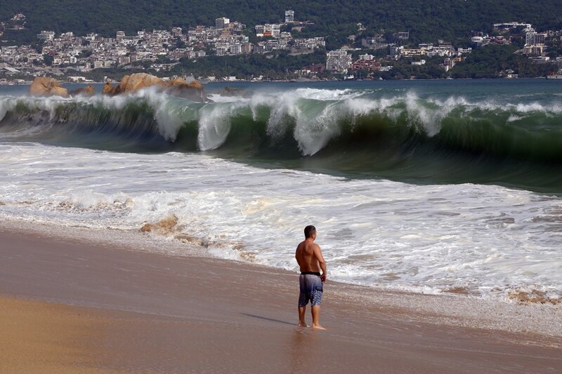 Un hombre observa las olas del mar en una playa de Acapulco