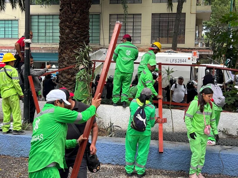 Trabajadores de la construcción instalando una valla metálica