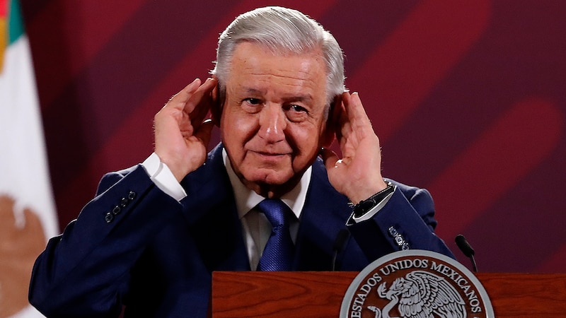 El presidente López Obrador se tapa los oídos durante una conferencia de prensa.