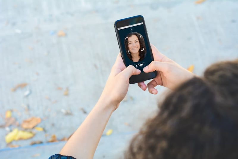 persona viendo su celular, refleja su rostro En china multaron a barias cuentas de redes sociales por utilizar los rostros de celebridades para estafar