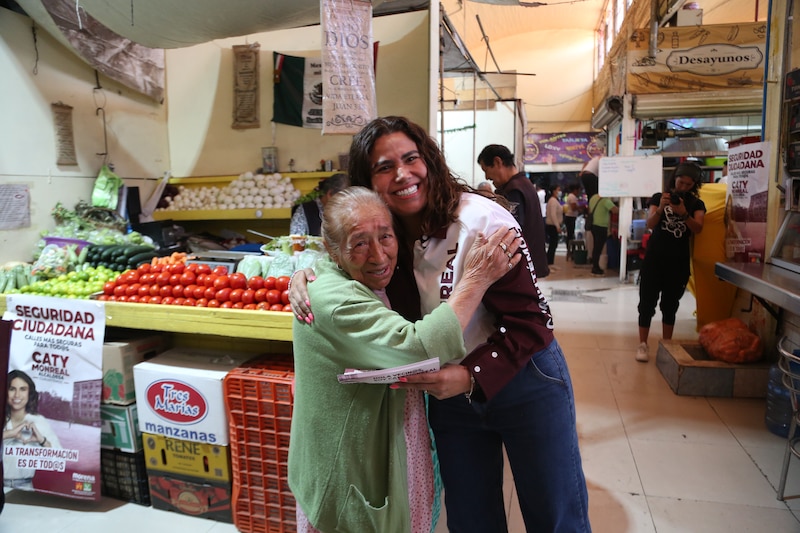 Title: La candidata a la alcaldía de Morena, Caty Monreal, saluda a una mujer en un mercado de la Ciudad de México.