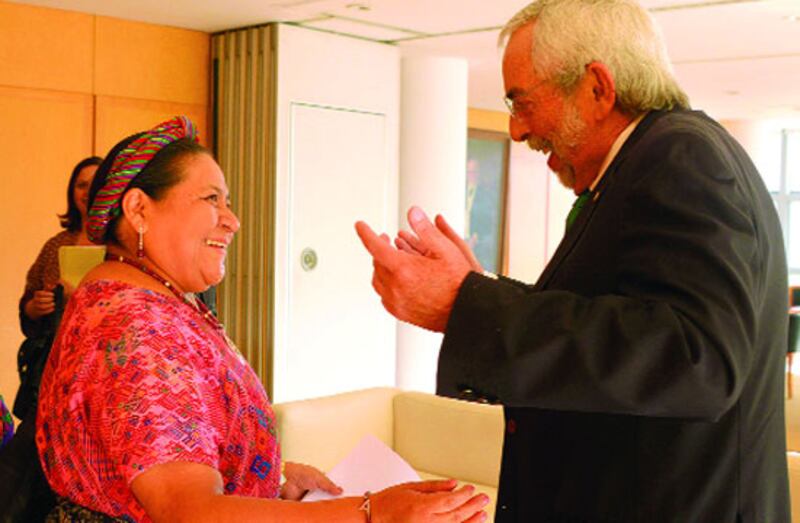 Rigoberta Menchú Tum recibe un premio de manos de un hombre en traje.
