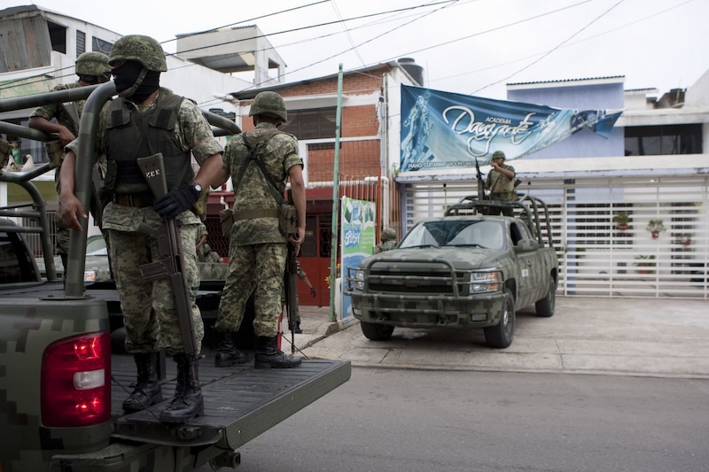 Militares mexicanos patrullan una calle en una ciudad.