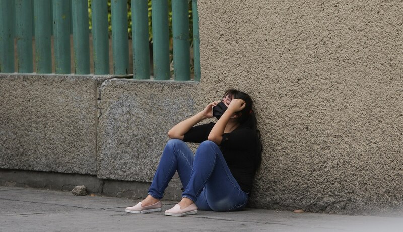 Mujer sentada en la acera con la cabeza entre las manos