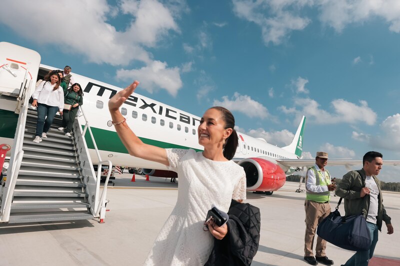 La presidenta López Obrador saluda a la gente desde la escalerilla del avión