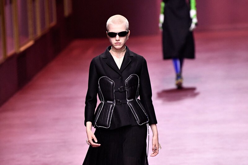La modelo lleva un traje de chaqueta negro con un corsé incorporado.