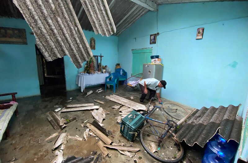 Un hombre limpia el desorden en su casa después de un huracán.