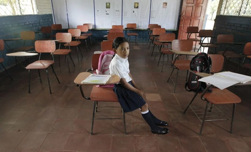 Niña sentada en una silla en un aula vacía