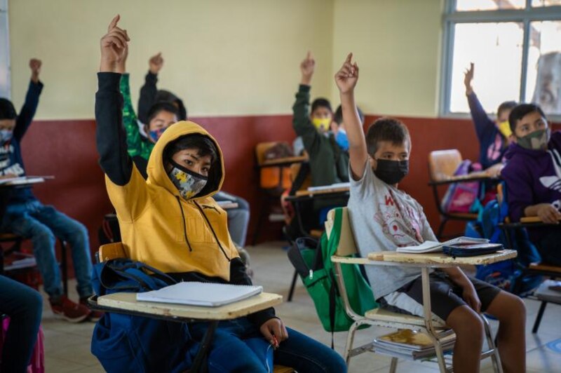 Niños en el aula levantando la mano para responder