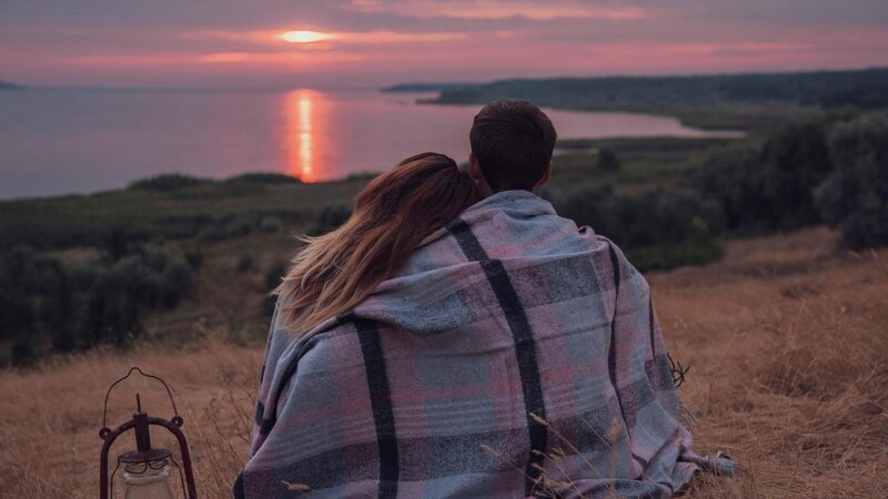 Pareja viendo el atardecer en una colina