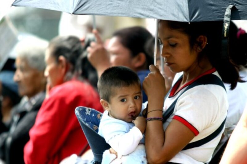Madre sosteniendo a su bebé bajo la lluvia