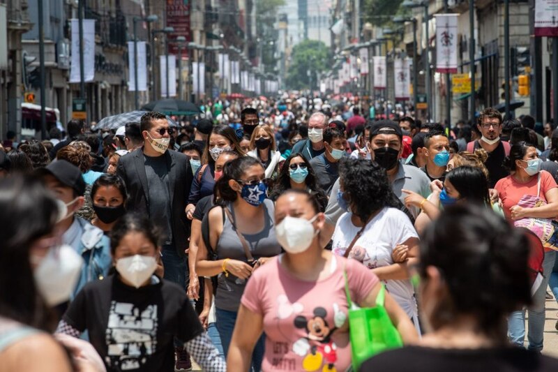 Multitud de personas con mascarillas caminando por una calle en el centro de la ciudad