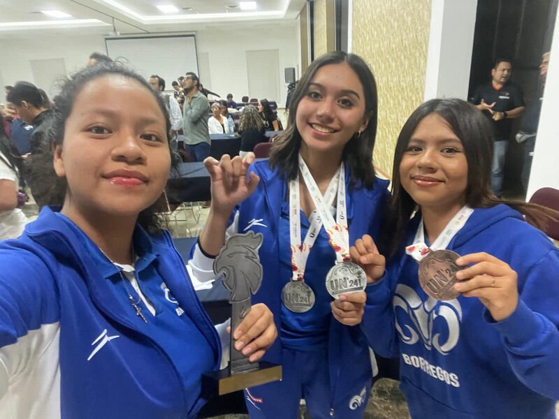 Tres jóvenes atletas reciben medallas en una ceremonia de premiación.