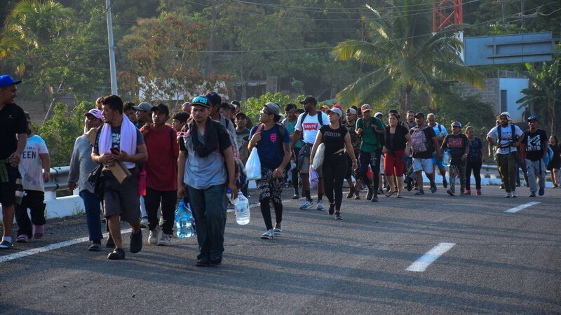 Migrantes caminan en grupo por una carretera