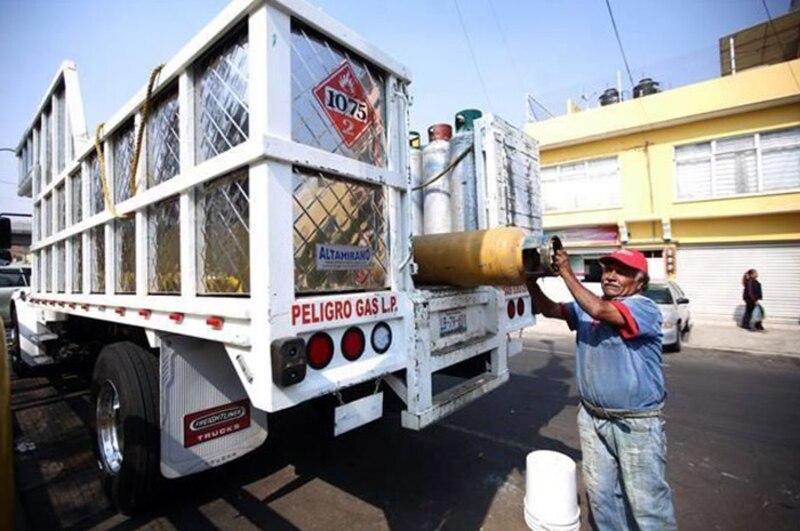 Un hombre carga un tanque de gas LP en un camión