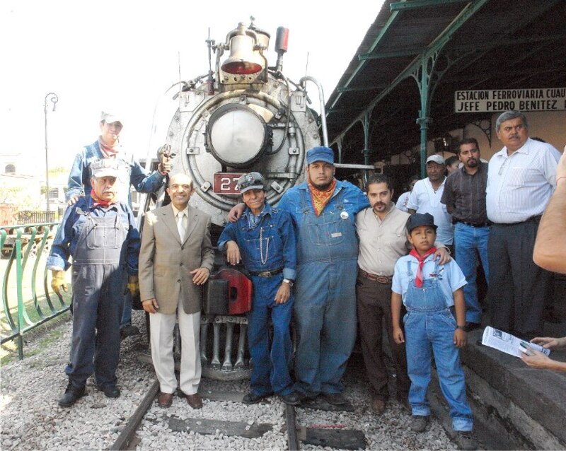 El personal del museo posa junto a una locomotora de vapor.