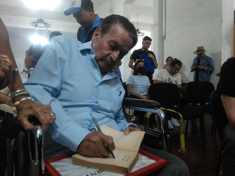 El expresidente ecuatoriano Rafael Correa firma un libro durante un evento público.