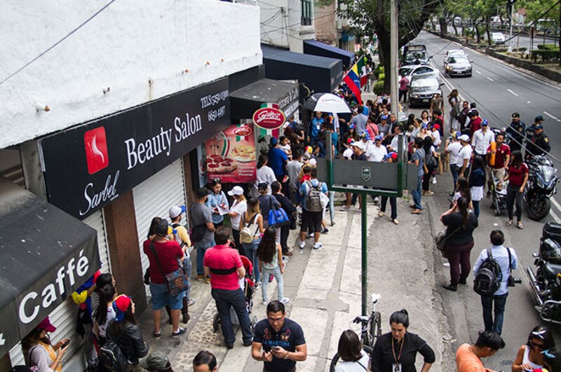 Larga fila de personas esperando para entrar a un local comercial