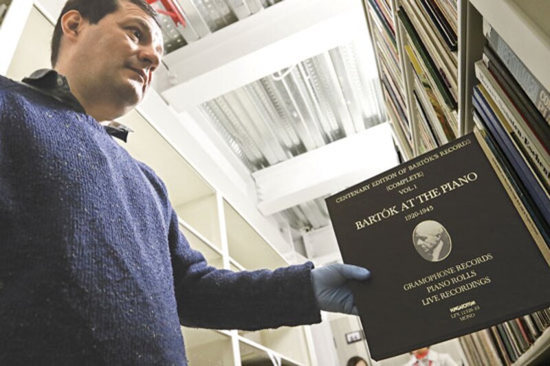 Un hombre sostiene un libro de partituras en una biblioteca