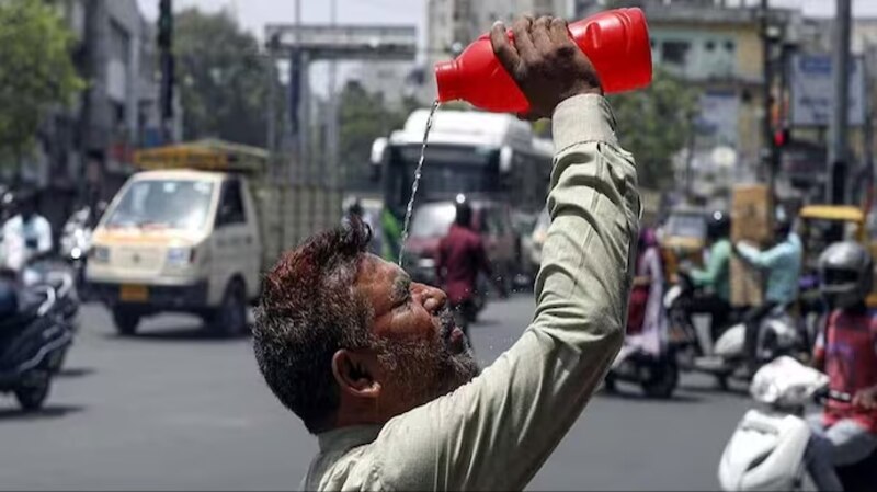 Un hombre se refresca del calor del verano echándose agua en la cabeza