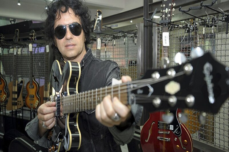 El músico argentino Fito Páez prueba una guitarra en una tienda de música.