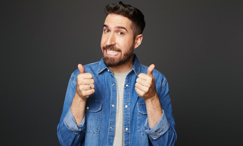 Hombre feliz con barba y camisa azul dando pulgares arriba