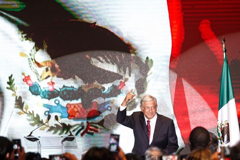 El presidente López Obrador da un discurso frente a una bandera de México.