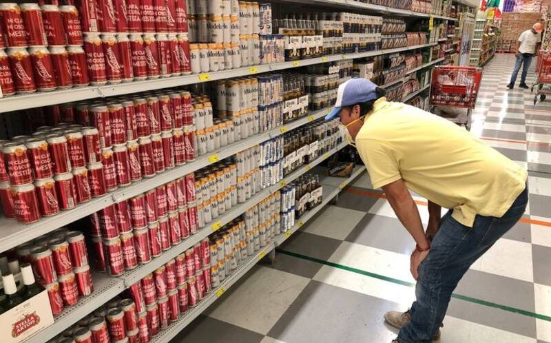 Hombre mirando latas de cerveza en el supermercado