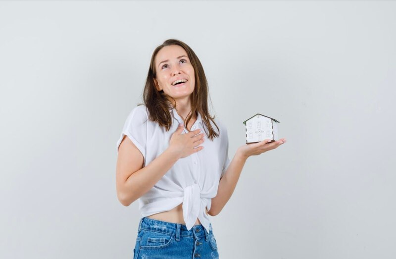 Mujer sosteniendo una casa en miniatura