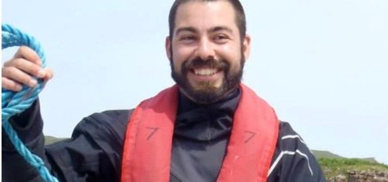 El biólogo marino sonríe mientras sostiene una cuerda