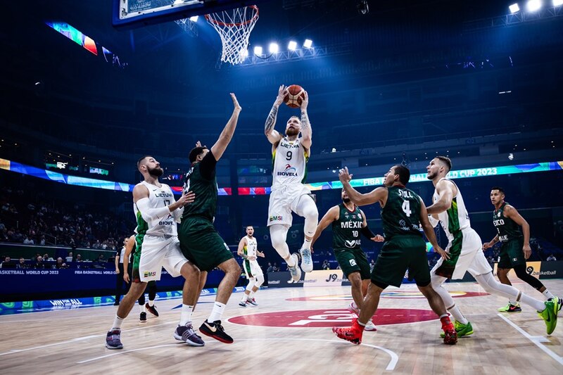 Un jugador de baloncesto lituano se eleva para encestar la pelota mientras es defendido por un jugador mexicano.