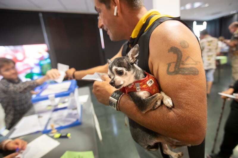 Un hombre con un perro en brazos vota en las elecciones