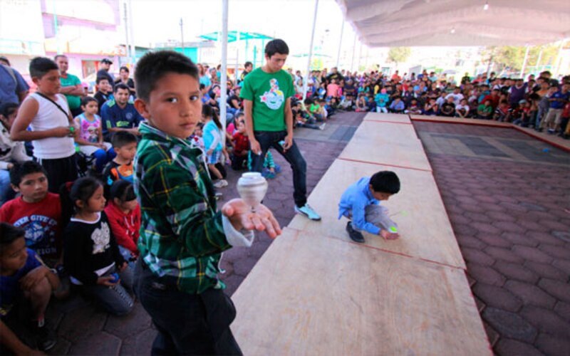 Niños jugando a la perinola en un torneo