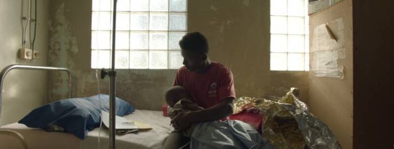 Un padre sostiene a su hijo enfermo en un hospital.