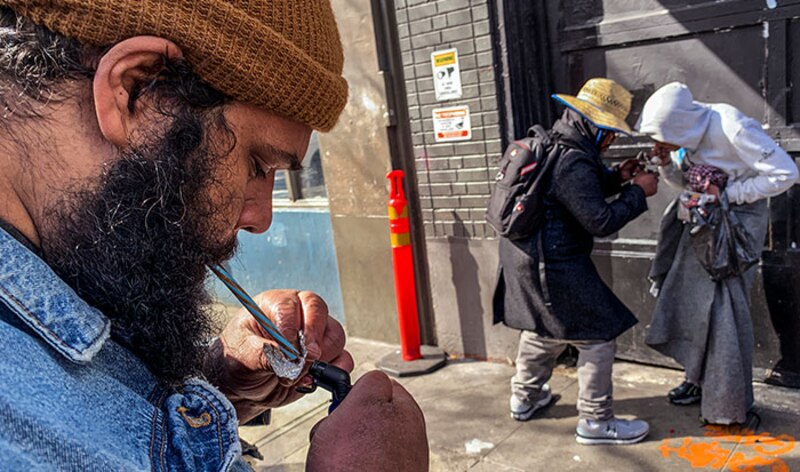 Un hombre fumando una pipa de crack