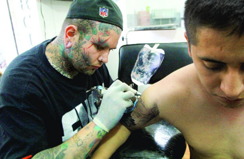 Un hombre se tatúa el brazo