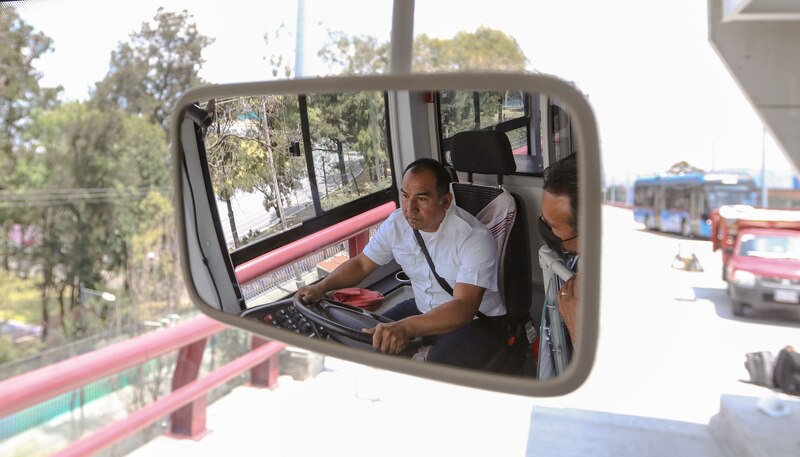 El conductor del autobús mira por el espejo retrovisor