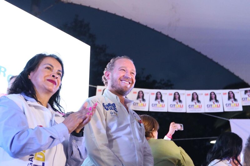 Candidata y candidato sonríen durante un mitin político