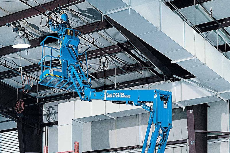 El trabajador está usando una plataforma elevadora para llegar al techo