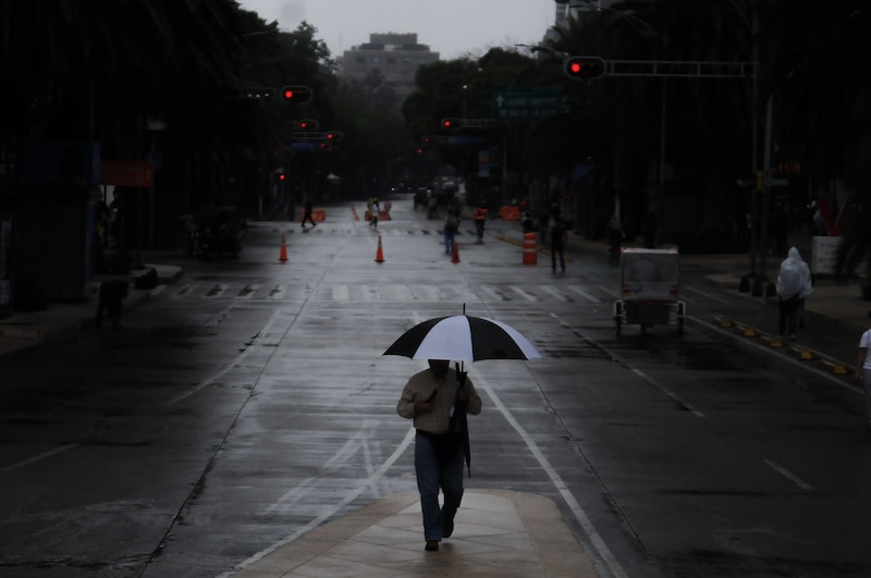 Un hombre camina bajo la lluvia en una calle de la ciudad.