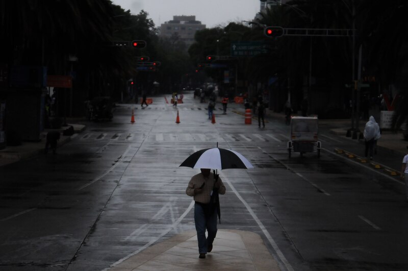 Un hombre camina bajo la lluvia en una calle de la ciudad.