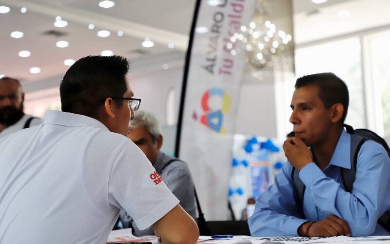 Dos hombres están hablando en una feria de empleo.