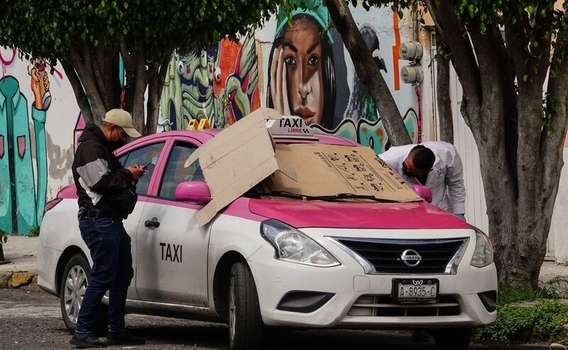 Taxista revisa el celular mientras espera a su pasajero